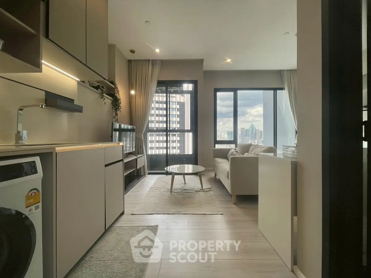 Modern living room with city view, featuring sleek furniture and integrated kitchen appliances.