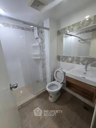 Modern bathroom with glass shower and stylish vanity in contemporary apartment.