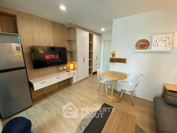 Modern living room with stylish decor, wall-mounted TV, and cozy dining area.