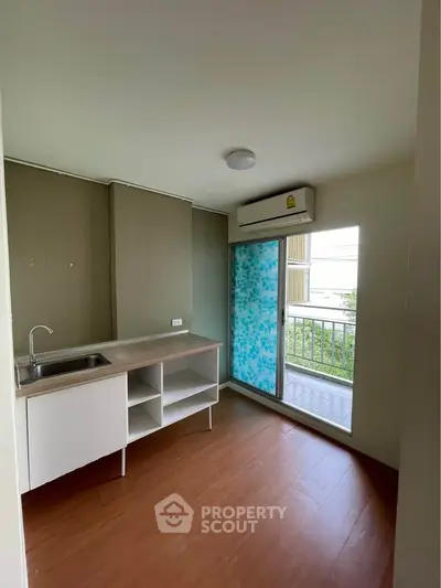 Compact kitchen with balcony access and air conditioning in modern apartment.