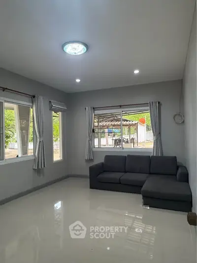 Spacious living room with modern sofa and large windows offering natural light.