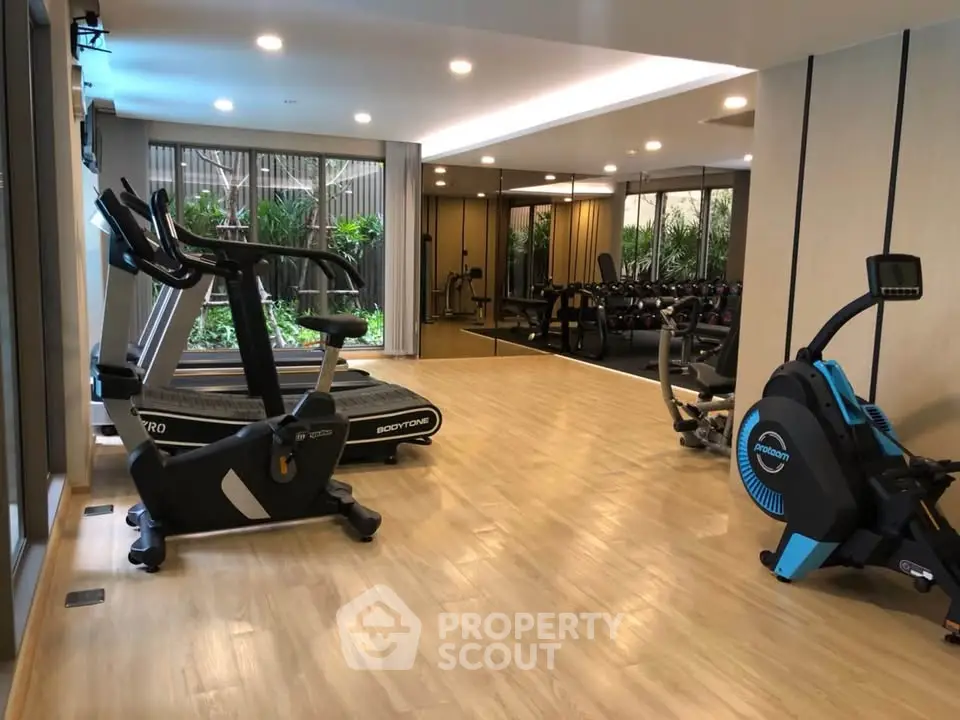 Modern gym with state-of-the-art equipment and large windows overlooking greenery.