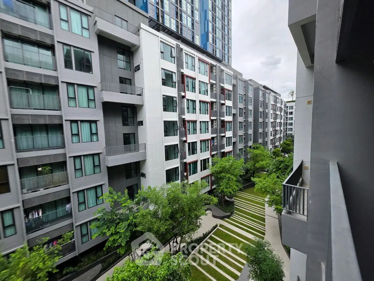 Modern apartment complex with lush green courtyard and contemporary architecture.