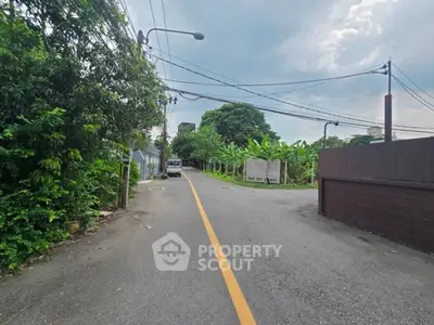 Quiet residential street with lush greenery and clear skies