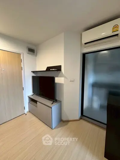 Modern living room with sleek TV stand and air conditioning unit, featuring minimalist design and wooden flooring.