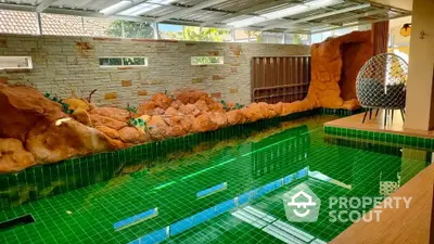 Luxurious indoor pool with unique rock features and green tiles in a modern home setting.