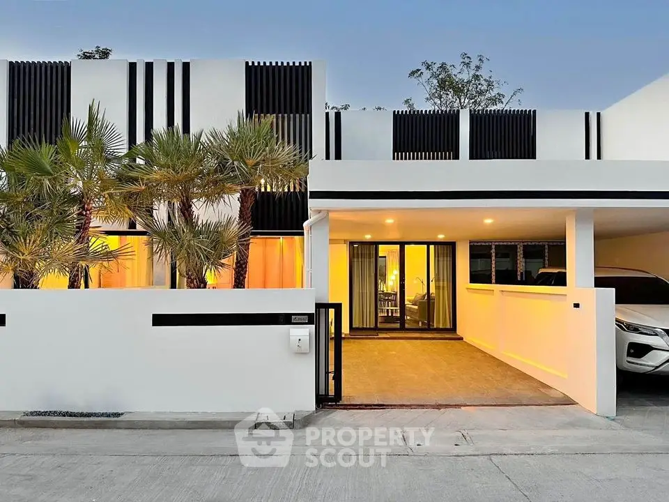 Modern minimalist house exterior with carport and palm trees at sunset