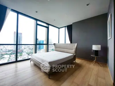 Spacious bedroom with floor-to-ceiling windows offering stunning city views in a modern high-rise apartment.