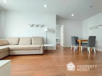 Spacious living room with polished hardwood floors, modern furniture, and ample natural light, perfect for urban living.