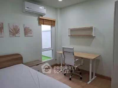 Modern bedroom with study area featuring a sleek desk and chair, air conditioning, and stylish decor.
