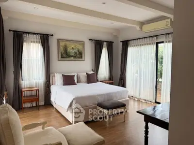 Spacious bedroom with elegant decor and large windows offering natural light