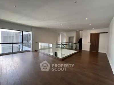 Spacious modern interior with wooden flooring and glass railing, perfect for stylish living.