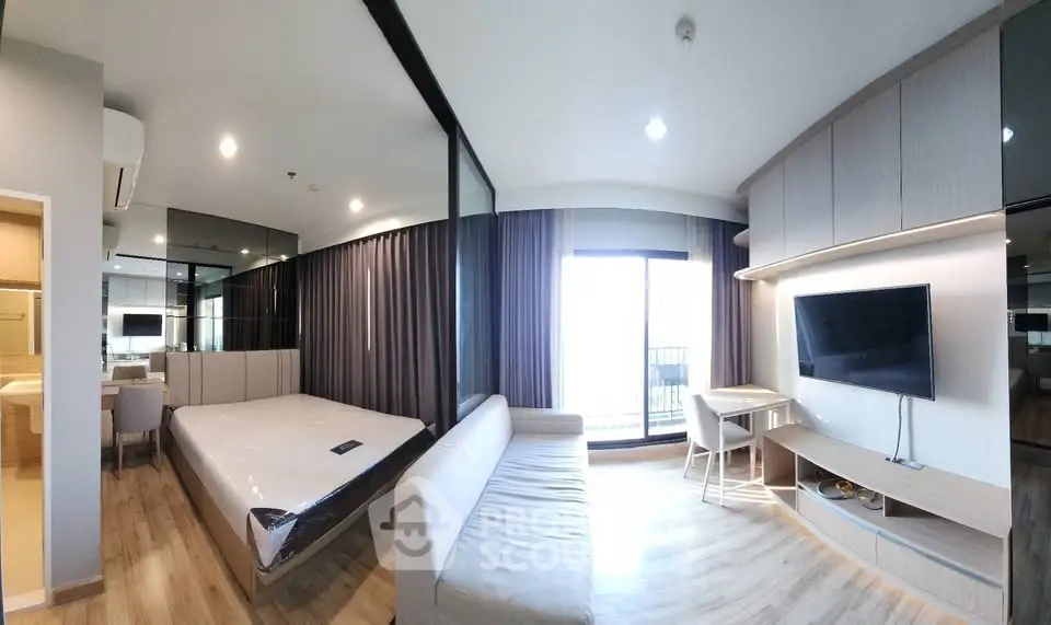 Modern studio apartment with open layout, featuring a cozy living area, bed, and balcony access.