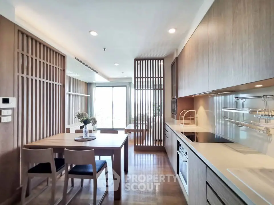 Modern kitchen with sleek cabinetry and dining area in open layout apartment.