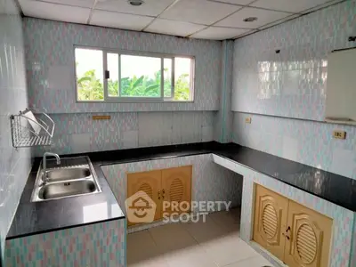 Spacious kitchen with modern countertops and ample natural light, perfect for culinary enthusiasts.