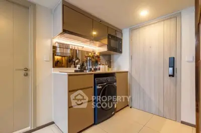 Modern compact kitchen with sleek cabinetry and built-in appliances in a stylish apartment.