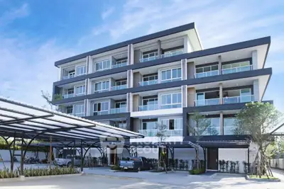 Modern multi-story apartment building with covered parking and landscaped surroundings.