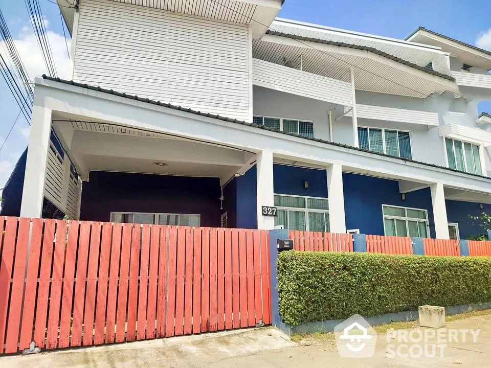 Charming two-story house with vibrant blue facade and red fence, perfect for family living.