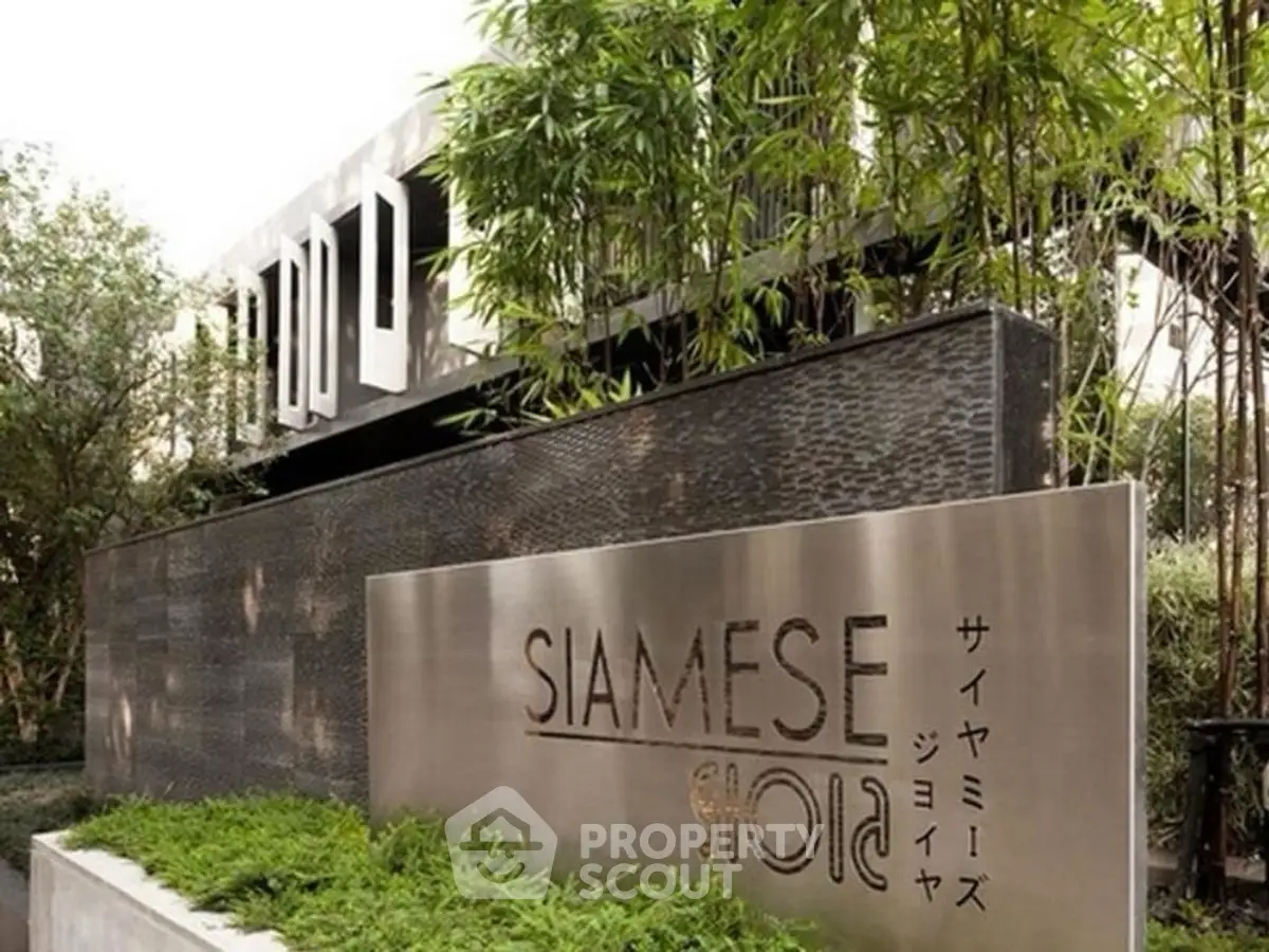 Modern building entrance with lush greenery and stylish signage
