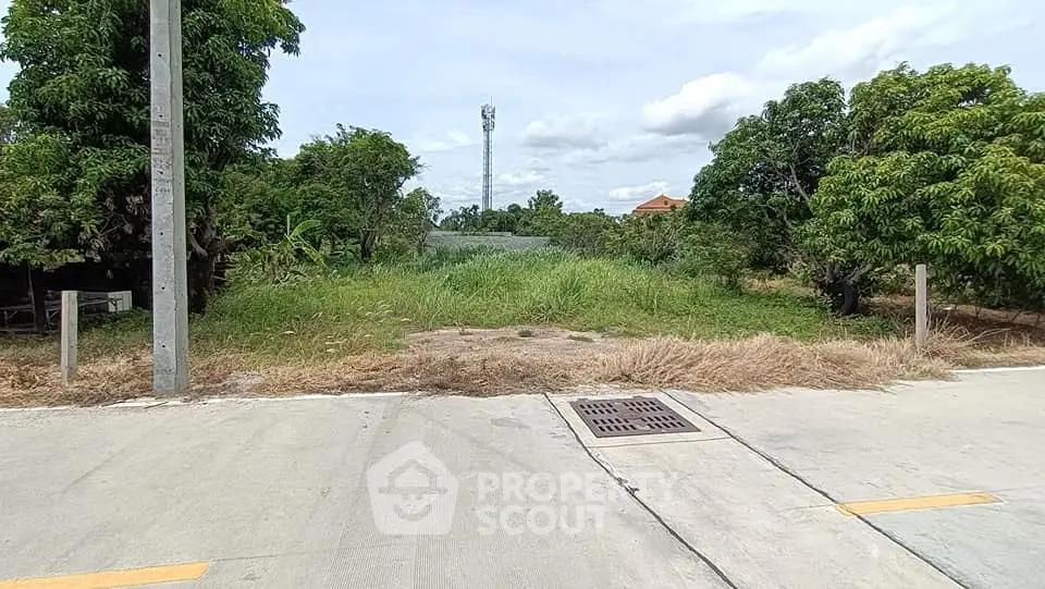 Vacant land plot with lush greenery and clear sky, ideal for development opportunities.
