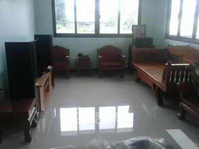 Spacious living room with polished floors and wooden furniture, featuring large windows for natural light.
