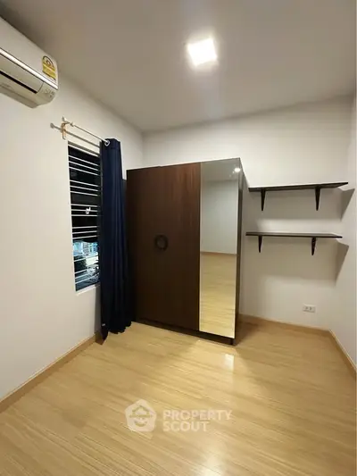 Spacious bedroom with wooden flooring and modern wardrobe