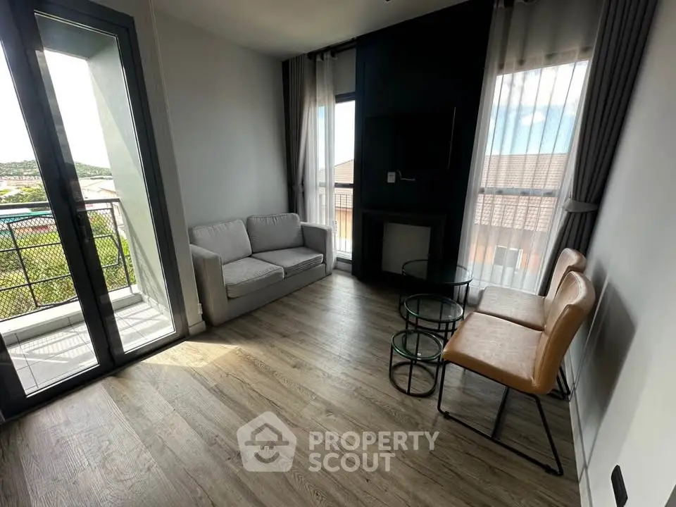 Modern living room with balcony view, featuring sleek furniture and abundant natural light.