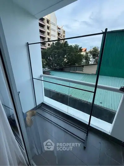 Modern balcony with glass railing and city view, ideal for relaxation and enjoying the outdoors.