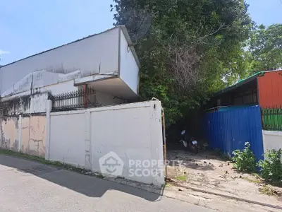 Exterior view of a property with a gated entrance and surrounding greenery.