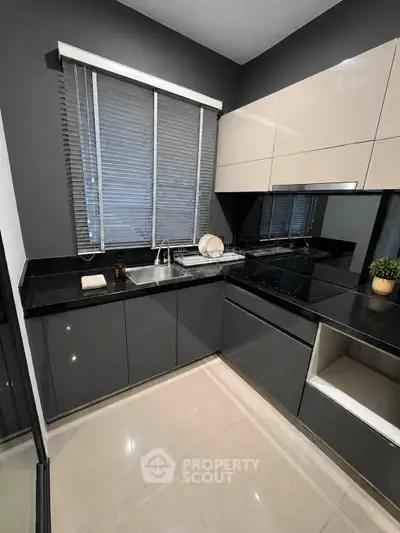 Modern kitchen with sleek cabinetry and black countertops in a stylish apartment.