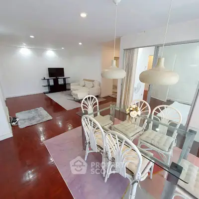 Spacious open-plan living and dining area with elegant glass table and cozy seating.