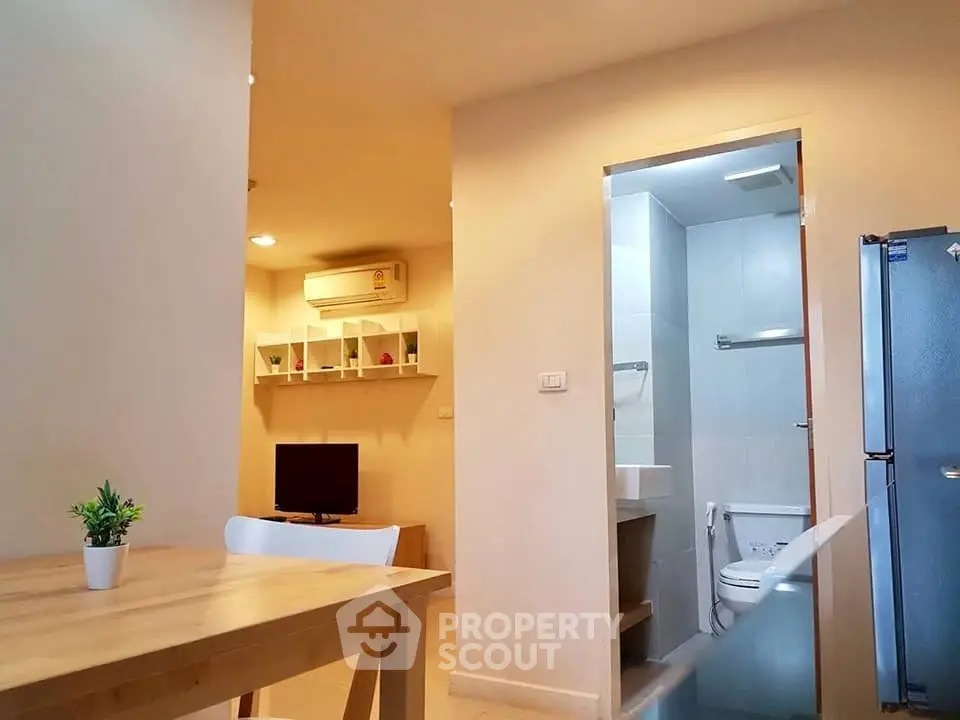Modern apartment interior with dining area, living room, and bathroom view.