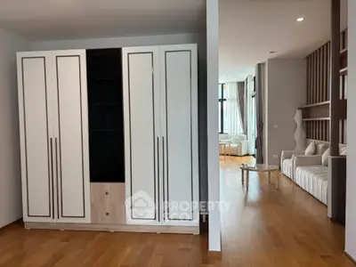 Spacious modern living area with elegant wooden flooring and built-in storage.