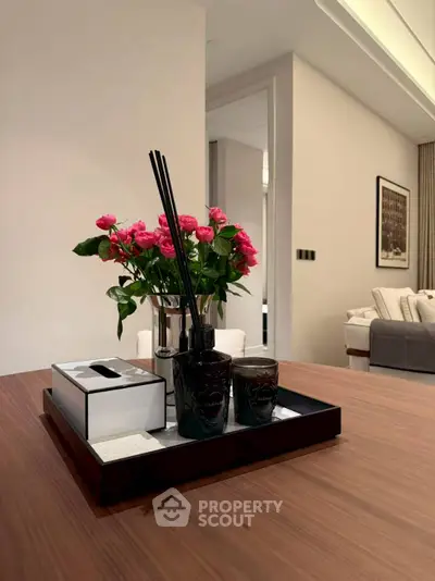 Elegant interior with stylish decor and vibrant pink roses on a wooden table.