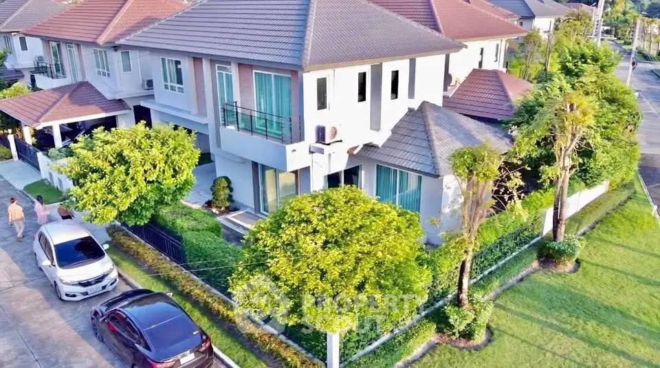Stunning aerial view of modern two-story house with lush garden and driveway in a serene neighborhood.