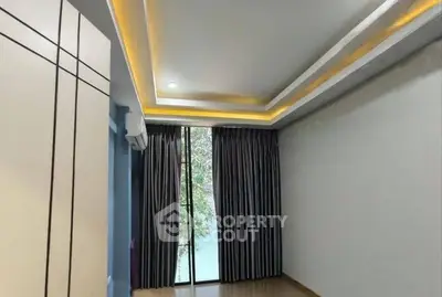 Spacious empty room with modern ceiling lights and large window view.