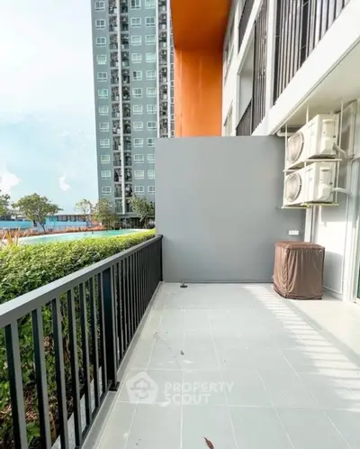 Spacious balcony with modern building view and air conditioning units, perfect for relaxation.