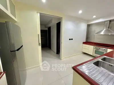 Modern kitchen with sleek design, featuring stainless steel appliances and red countertops.