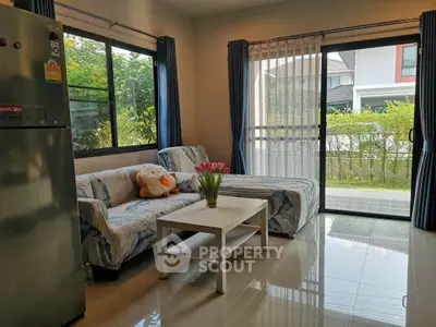 Bright living room with modern decor and garden view, featuring large windows and cozy seating area.