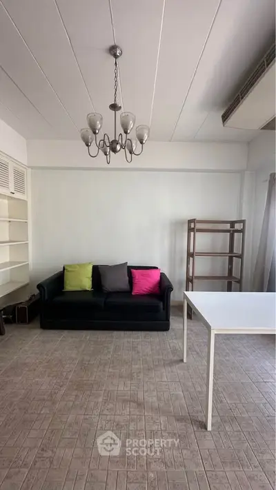 Spacious living room with modern chandelier and cozy sofa, perfect for relaxation and entertaining.