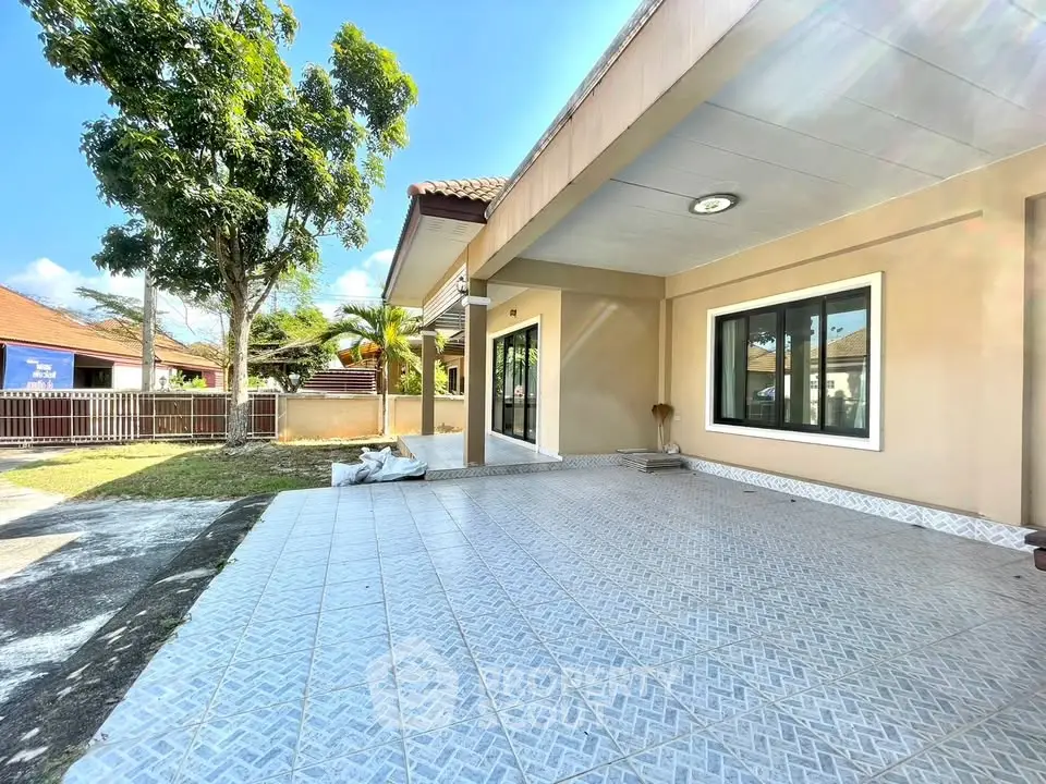 Spacious outdoor patio of a modern home with tiled flooring and lush greenery.