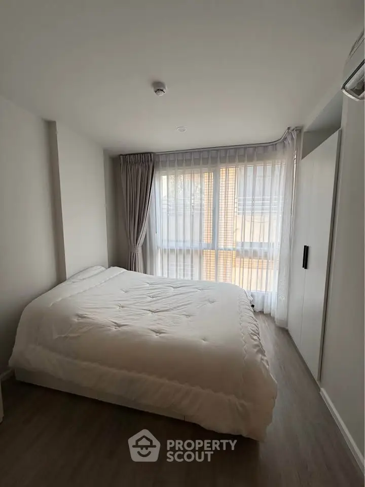 Spacious bedroom with large window and modern decor in a stylish apartment.