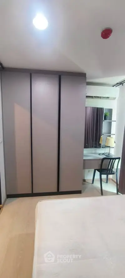 Modern bedroom with sleek wardrobe and cozy study area, perfect for urban living.