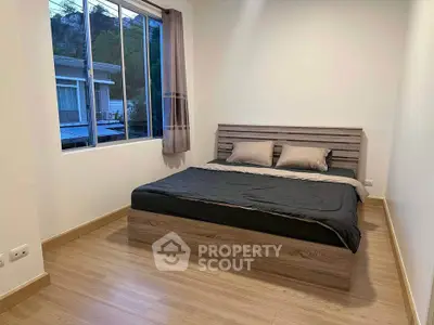 Cozy bedroom with modern wooden bed and large window view.