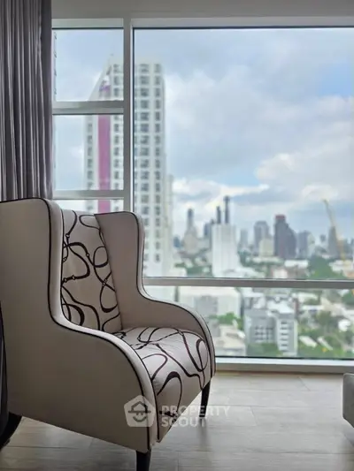 Stylish living room with city view through large window, featuring modern armchair.