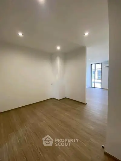 Spacious empty room with wooden flooring and recessed lighting, ideal for customization.