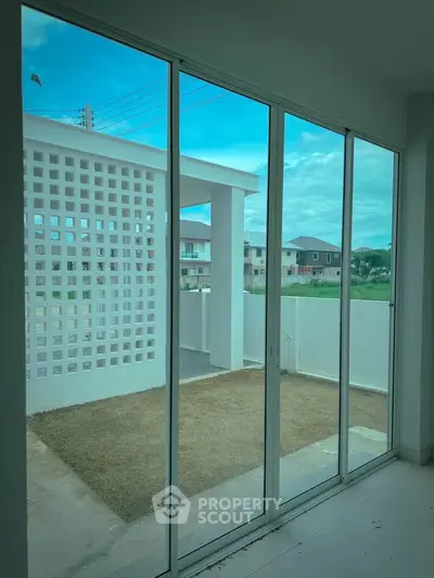 Spacious modern balcony with large glass doors and serene neighborhood view.