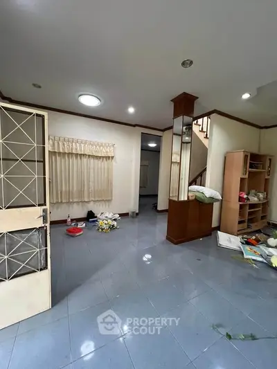 Spacious living room with tiled floor and staircase, ideal for modern family living.