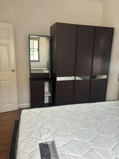 Cozy bedroom with modern wardrobe and mirror, perfect for stylish living.