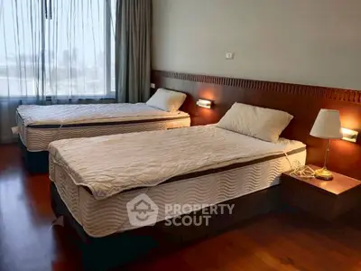 Spacious bedroom with twin beds and large window offering natural light.